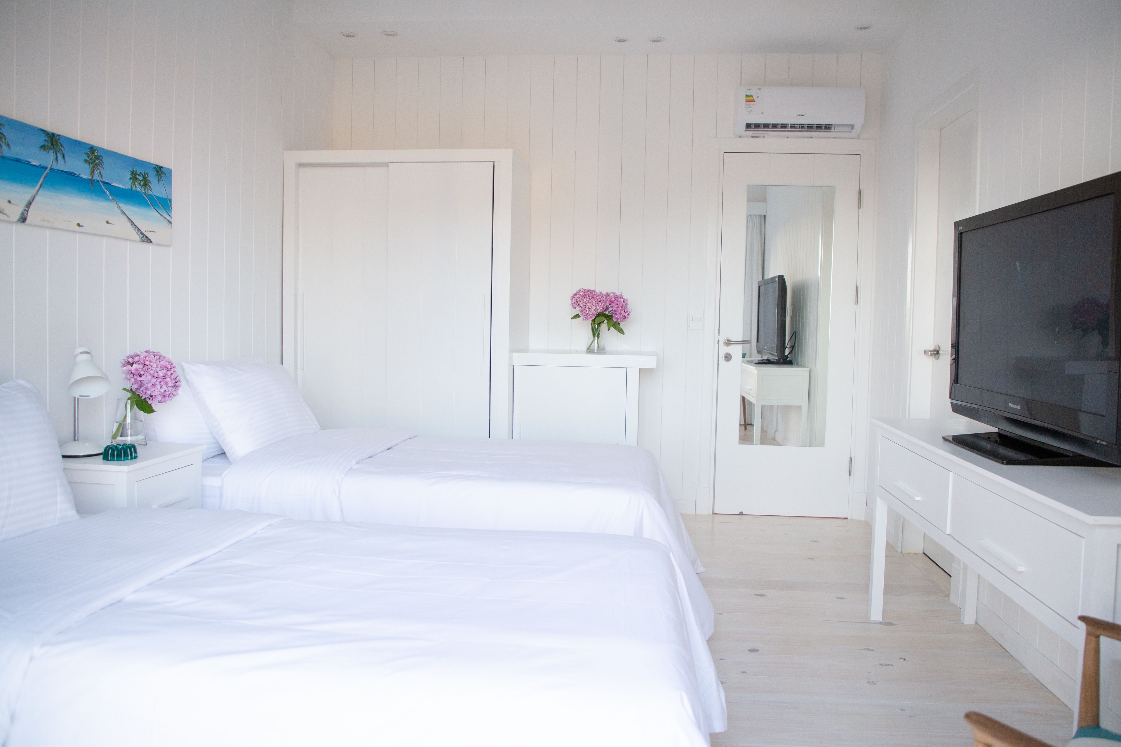 Un dormitorio con dos camas, un televisor y un aparador blanco.