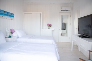 A bedroom with two beds, a TV, and a white dresser. - Casa Flor - Adults Only (Punta del Este)