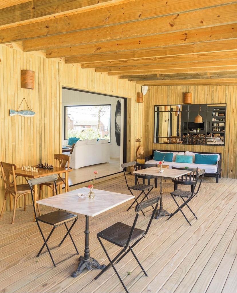 A wooden interior with a dining area, sofa, and a large window.