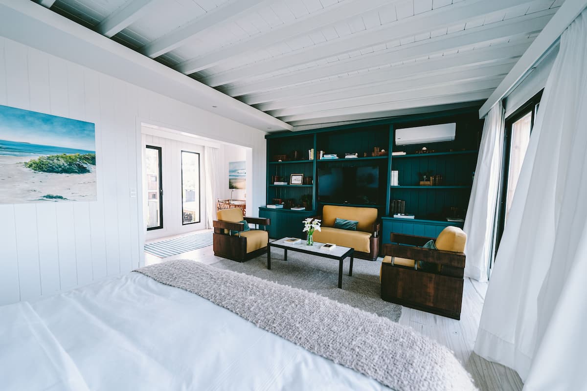 A modern bedroom with a large bed, a sofa, a coffee table, and a bookshelf.