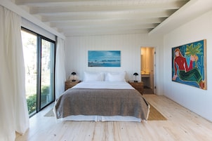 Un dormitorio con una cama grande, un cuadro en la pared y vistas a través de una ventana.