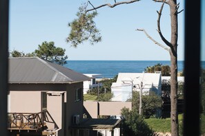 A residential area with houses, a tree, and a view of the sea. - Casa Flor - Adults Only (Punta del Este)