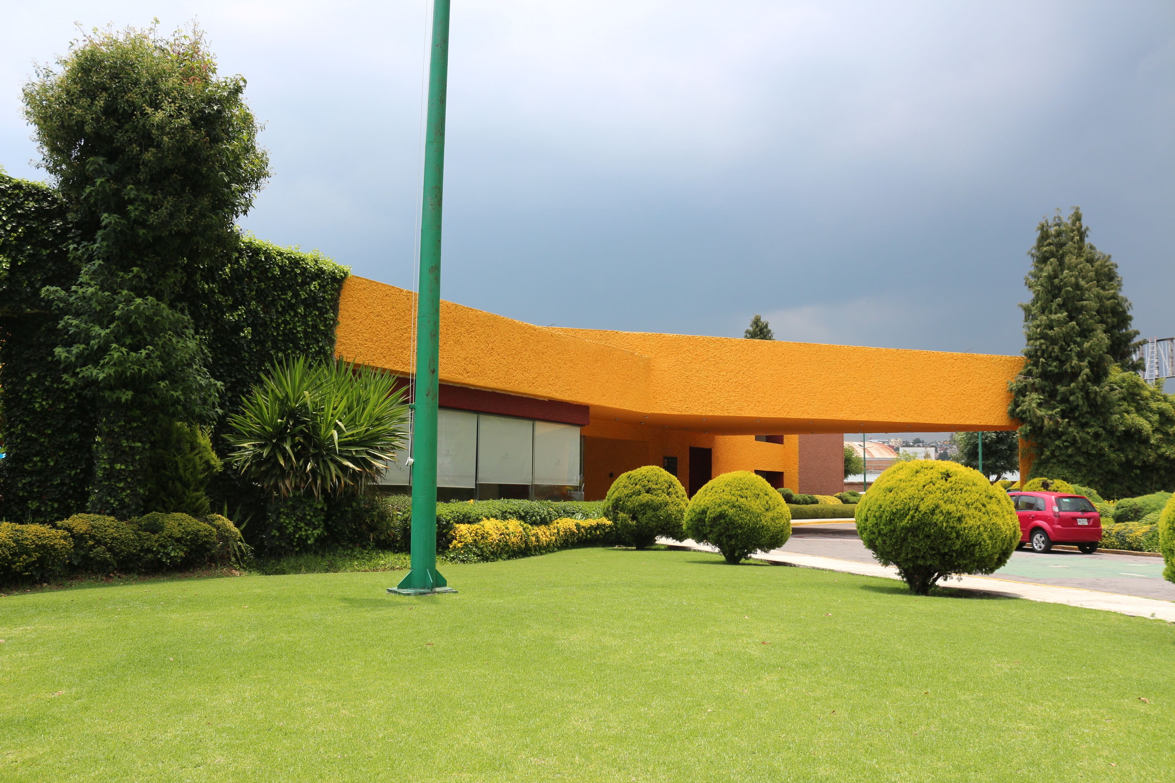 A building with a curved roof, surrounded by well-maintained lawns and hedges.