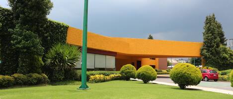 A building with a curved roof, surrounded by well-maintained lawns and hedges.