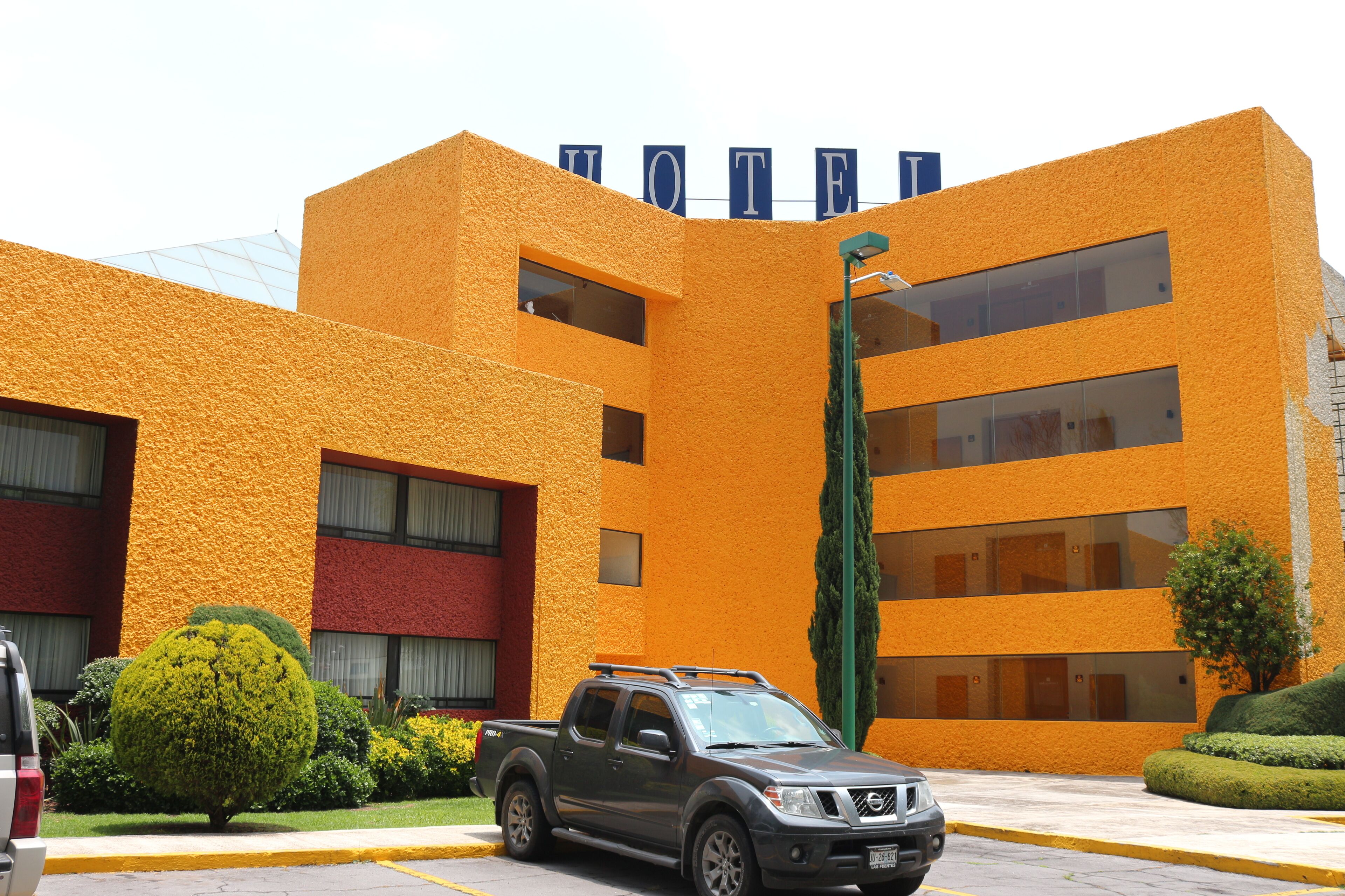 A building with a sign that reads "HOTEL" and a parked SUV.