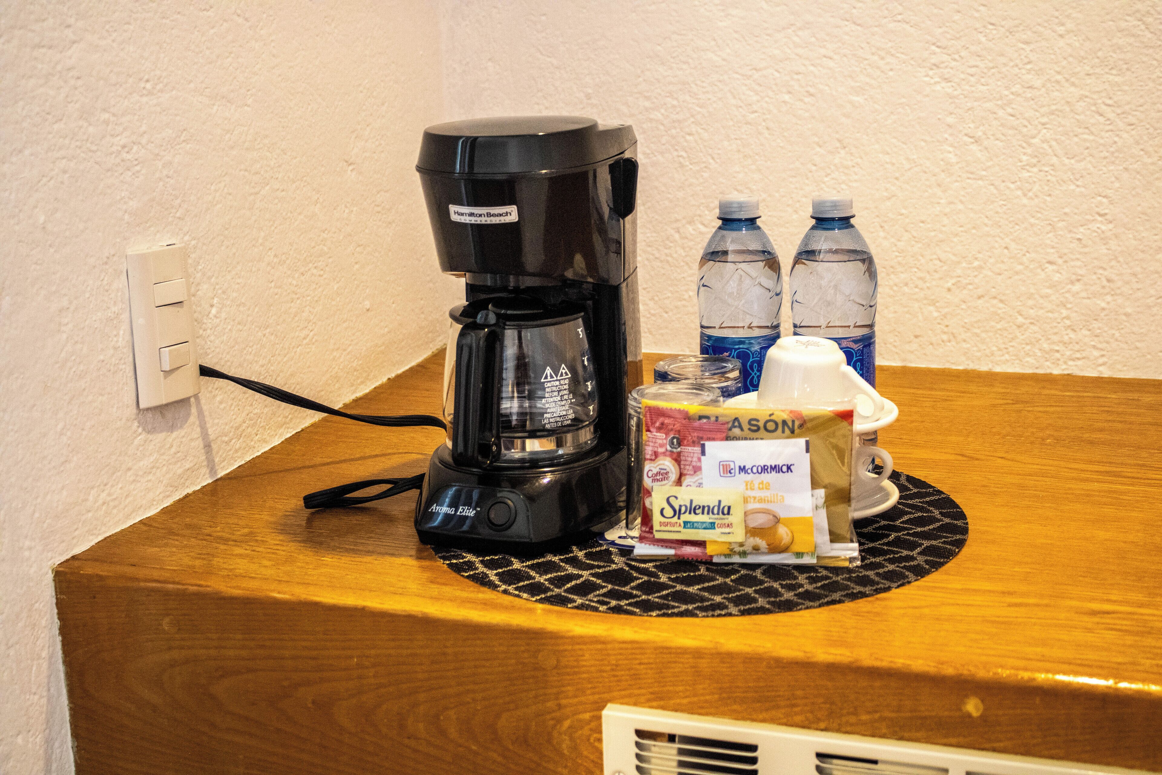 A coffee maker, two water bottles, a Splenda packet, and a McCormick spice packet on a wooden counter.
