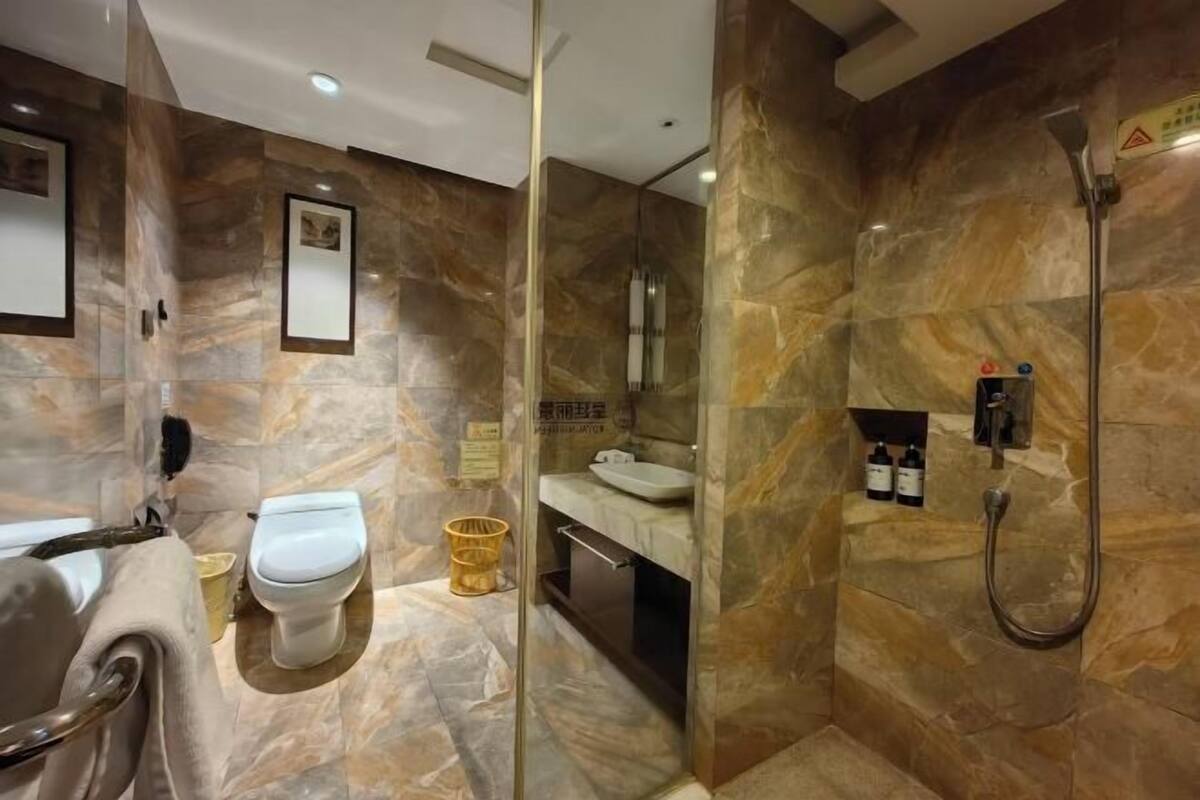 A modern bathroom with a glass-enclosed shower, a toilet, and a sink.