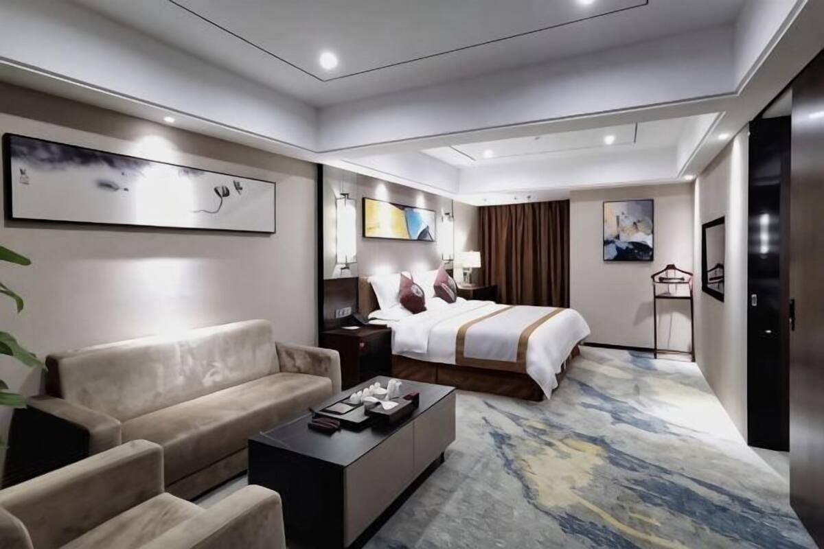 A hotel room with a bed, a sofa, a coffee table, and a TV.