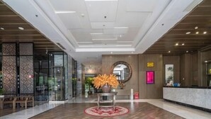 A modern lobby with a wooden floor, glass entrance, and a reception desk. - Huangting Lijing Hotel (Sanming)