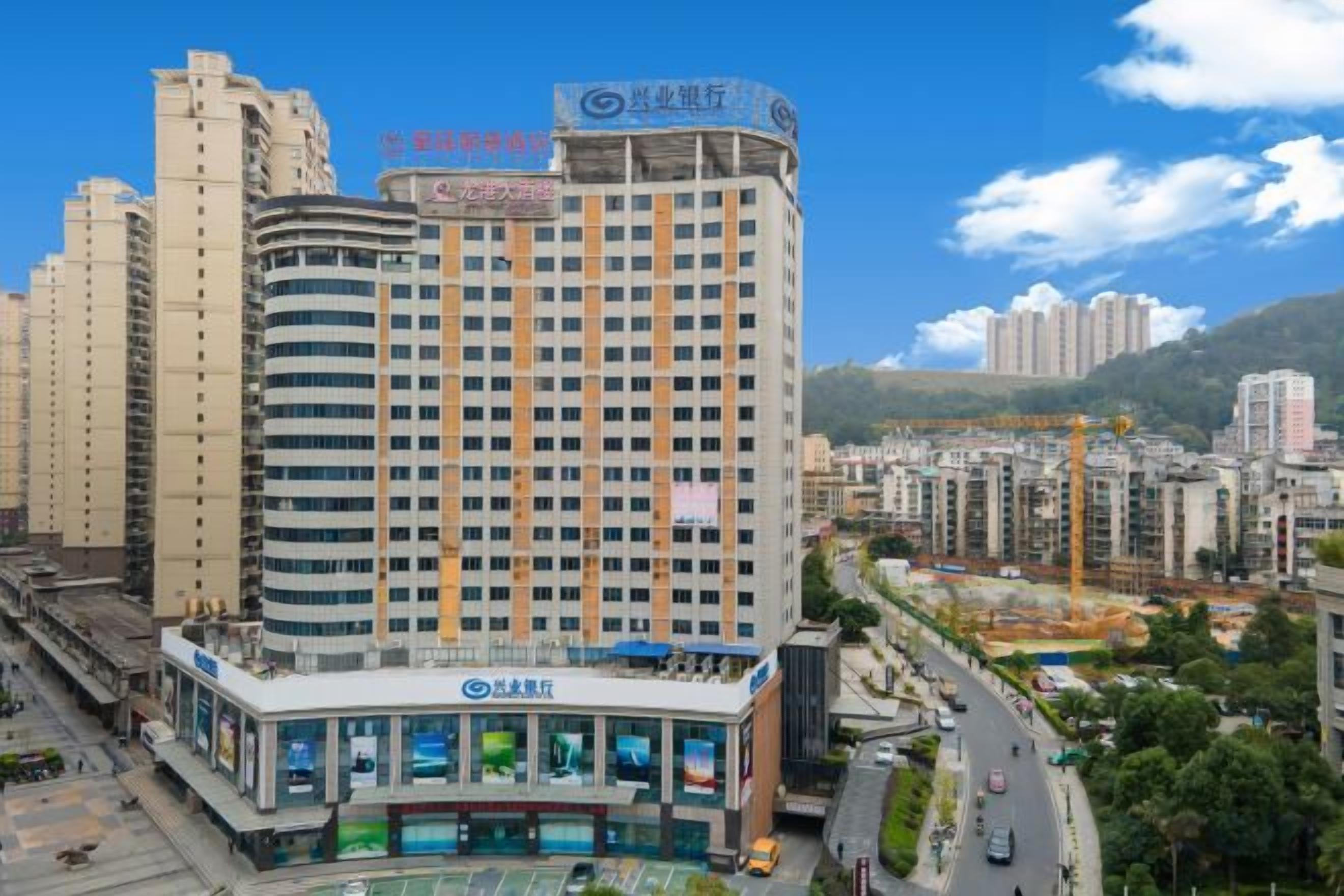 Un hotel de varios pisos con un letrero llamativo, un estacionamiento y vistas del paisaje urbano circundante.