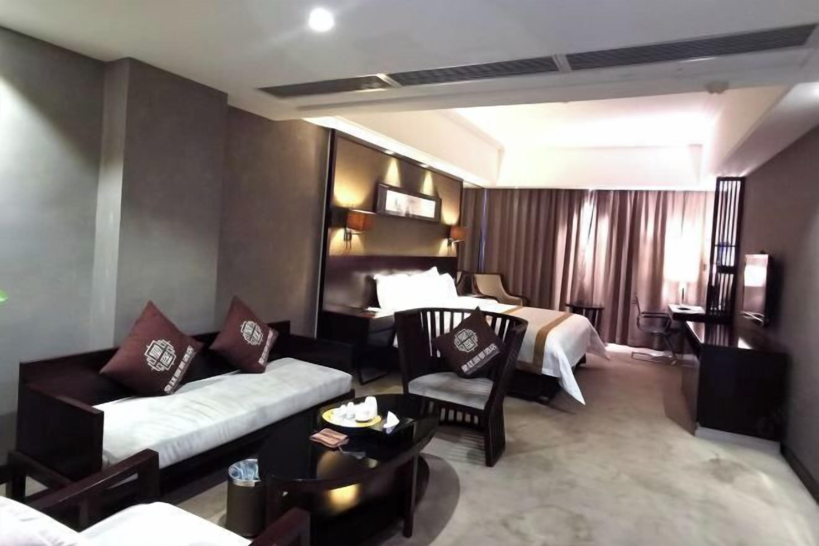 A hotel room with a bed, a sofa, a dining table, and a desk.
