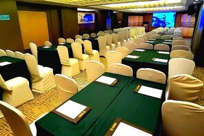 A conference room with rows of chairs and tables, equipped with name cards and a projection screen. - Huangting Lijing Hotel (Sanming)