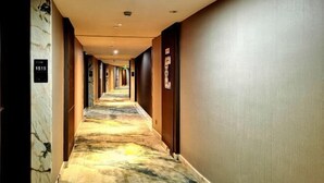 A hotel hallway with marble walls, numbered doors, and a patterned carpet. - Huangting Lijing Hotel (Sanming)