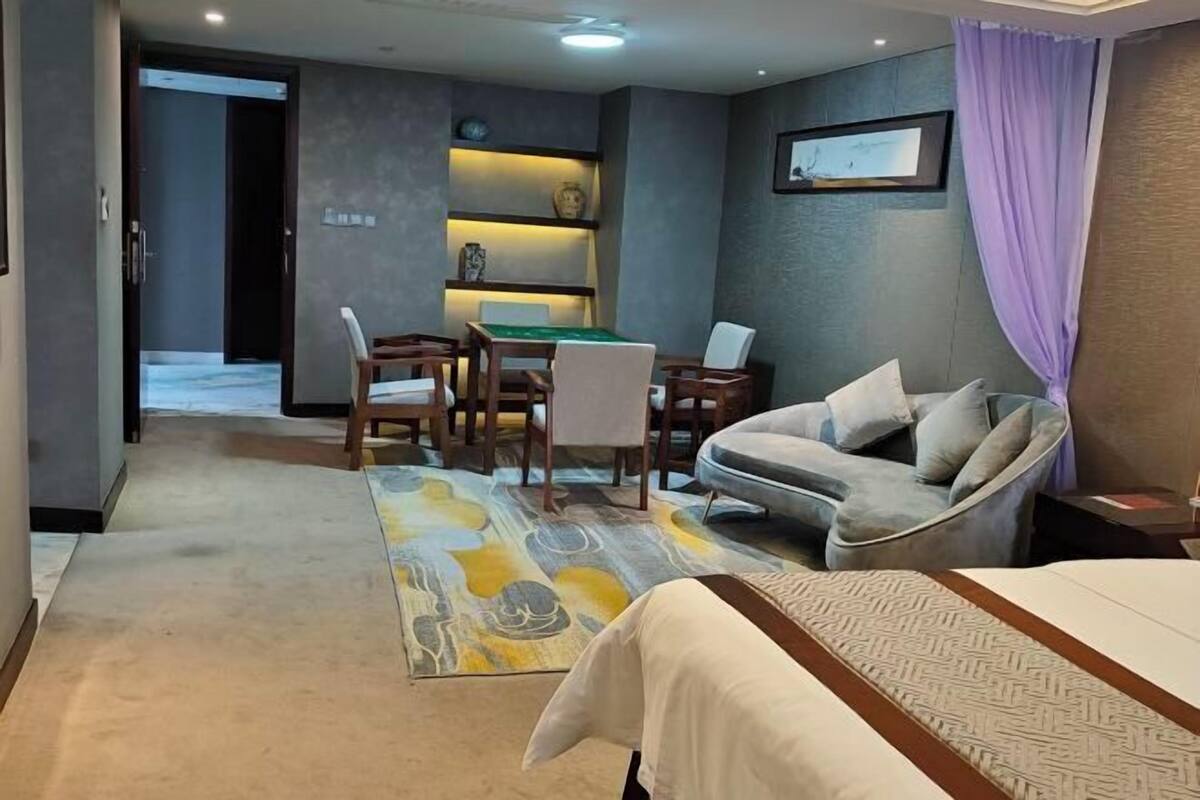 A hotel room with a bed, a sofa, a desk with a computer, a chair, and a small table.