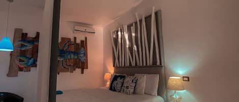 A bedroom with a bed, a nightstand, a chair, and wall art.