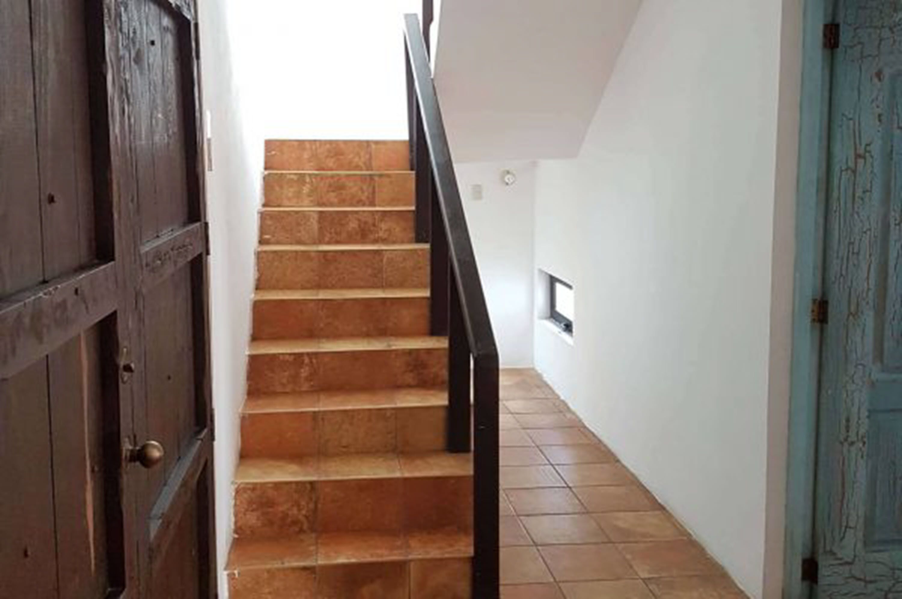 A staircase with wooden steps and black railings, leading to a landing with a small window.
