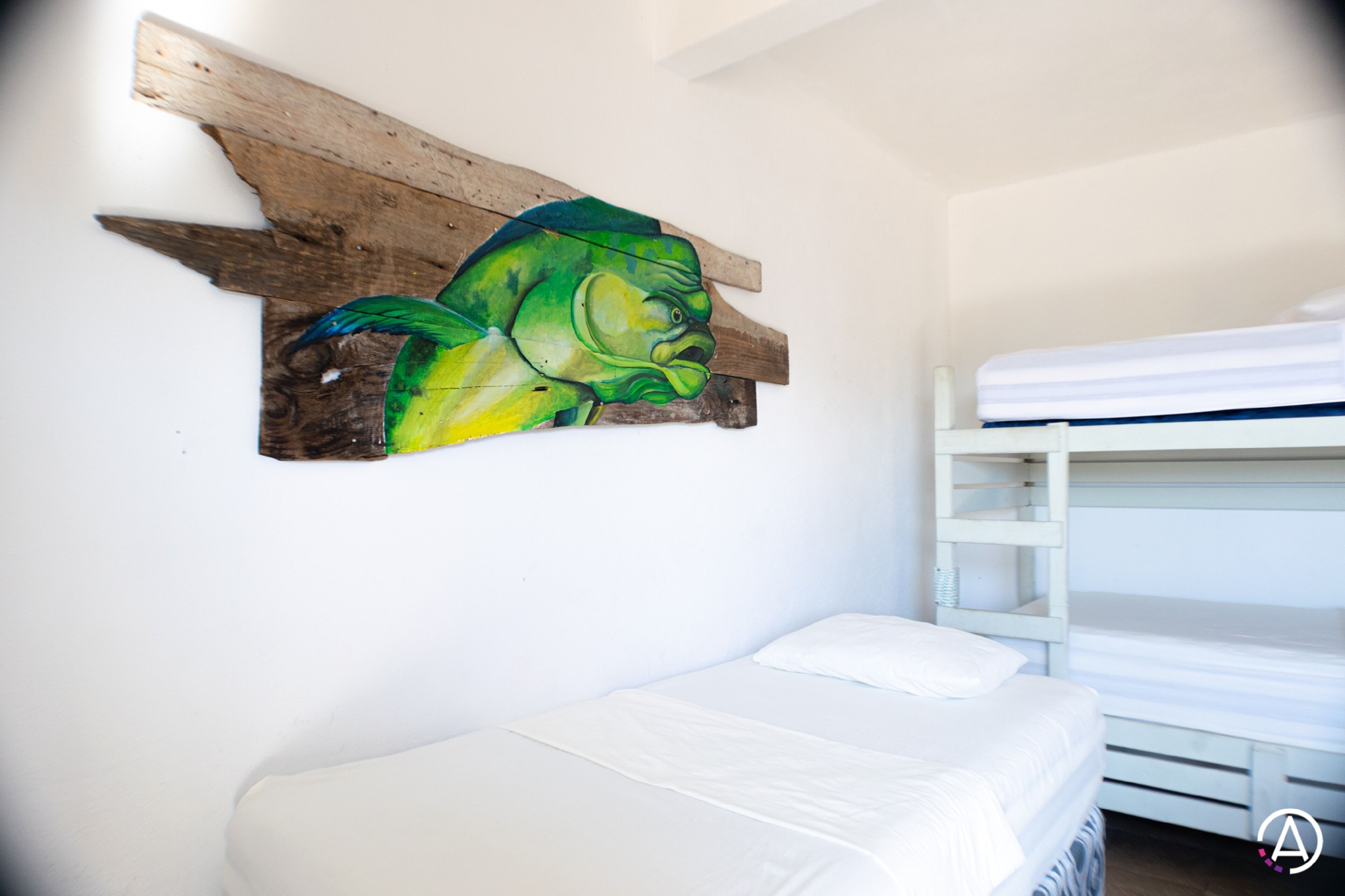 Una habitación con una cama litera y un cuadro de un pez colgado en la pared.