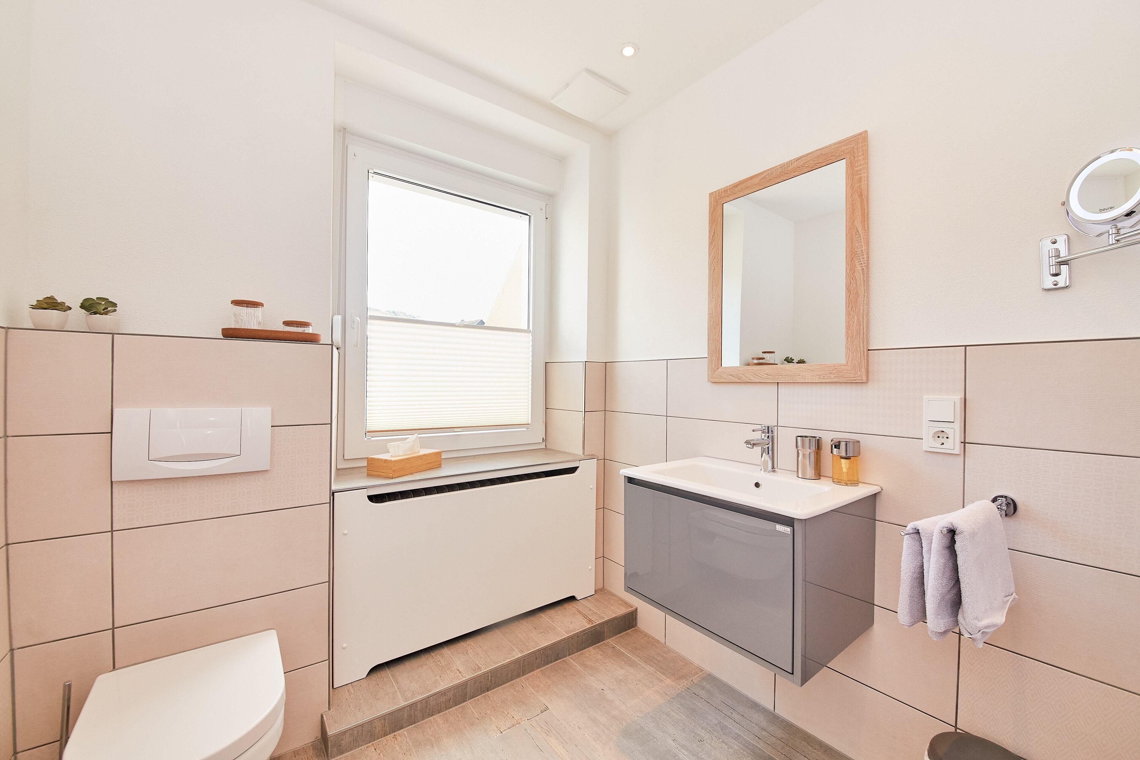Un baño moderno con inodoro, lavabo y ventana.