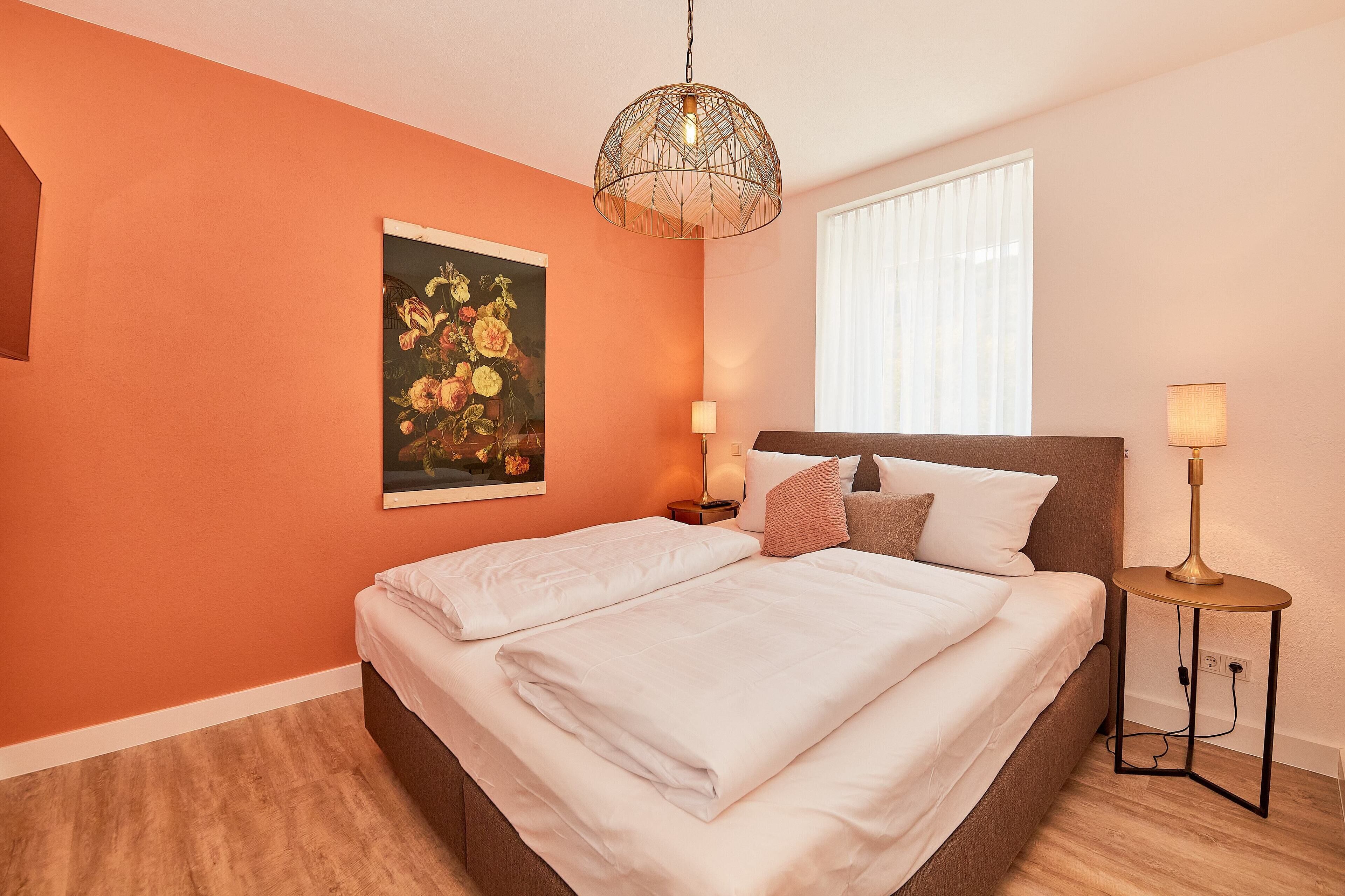 Un dormitorio con cama, un cuadro, una ventana y una lámpara.