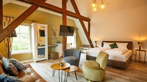 A bedroom with a bed, a TV, a sofa, a chair, and a small table. - Rochter Landhotel (Zeltingen-Rachtig)