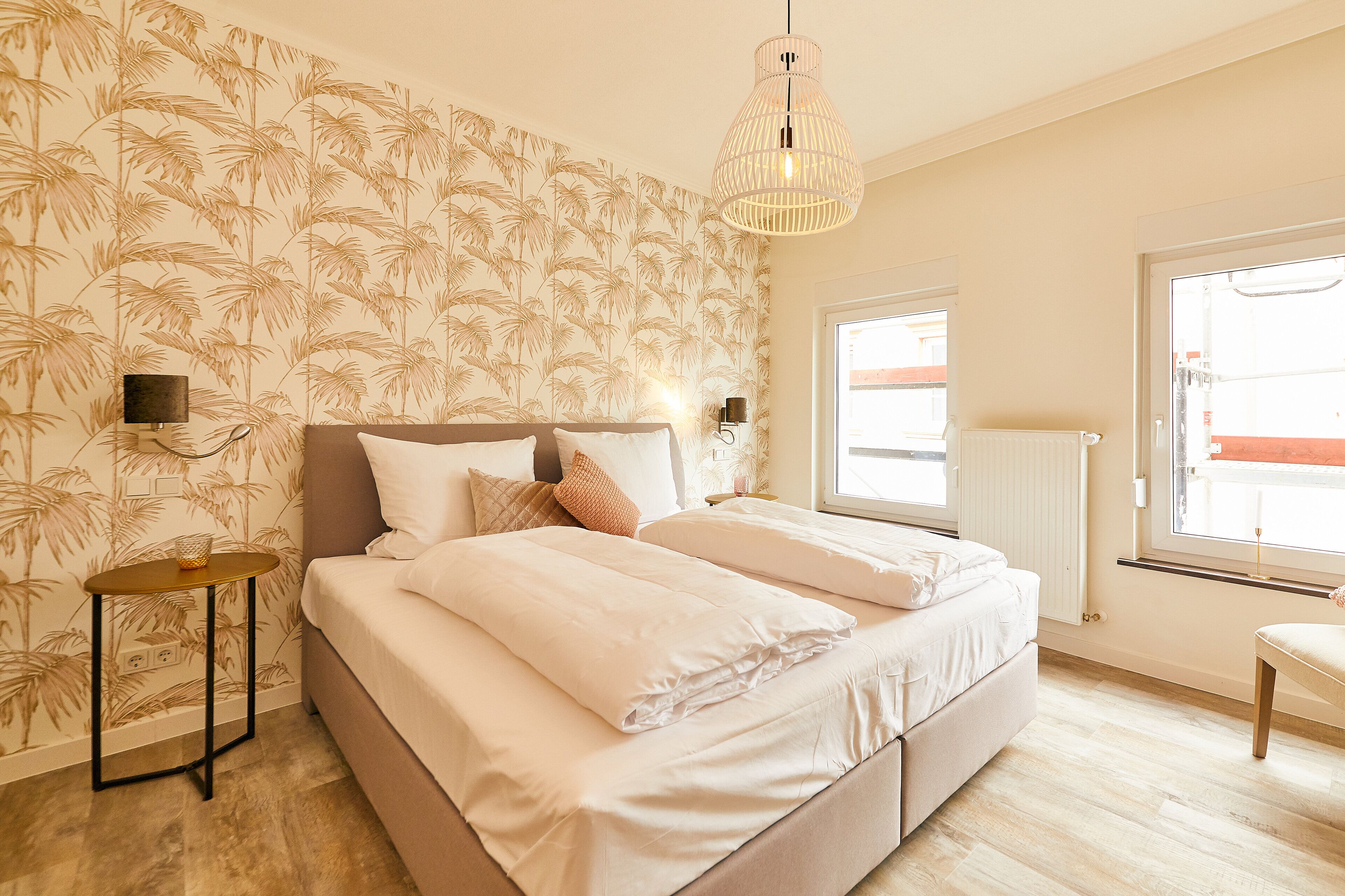 A bedroom with a bed, a bedside table, a lamp, and a window.