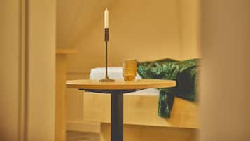 Ein Zimmer mit einem Bett, einem Tisch mit einer Kerze und einer grünen Decke.