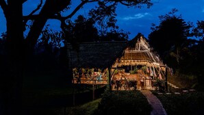 A thatched-roof structure with outdoor seating and a pathway leading to it.