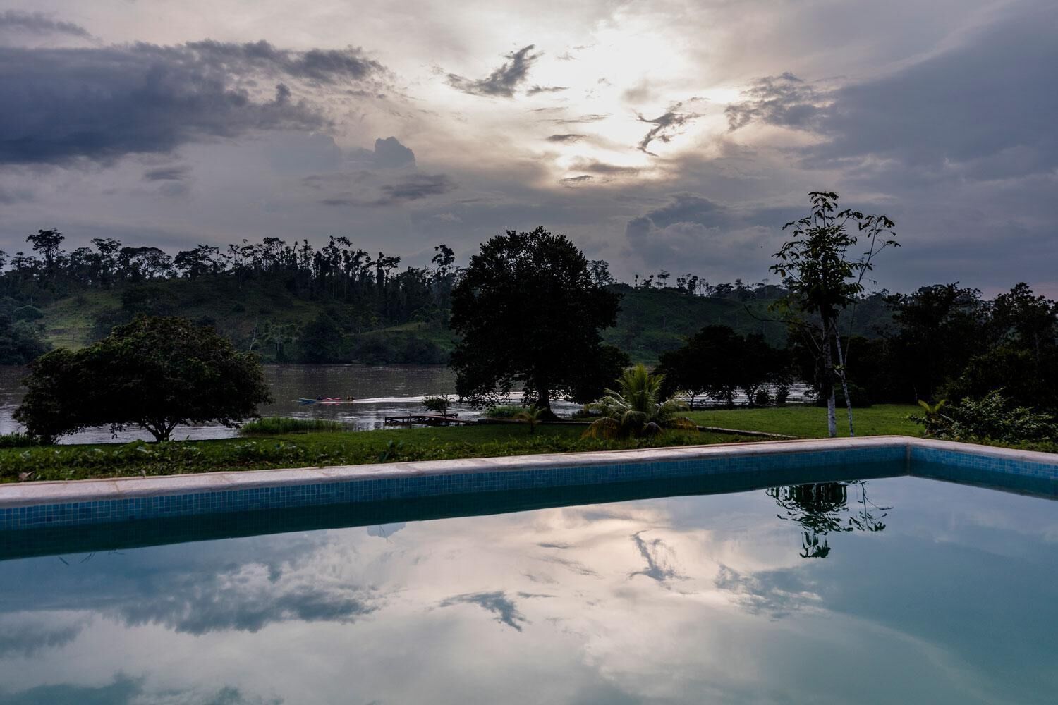 A swimming pool with a view of a lake and trees.