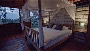 Una cama con dosel y cuatro columnas, con vistas al exterior a través de una ventana.