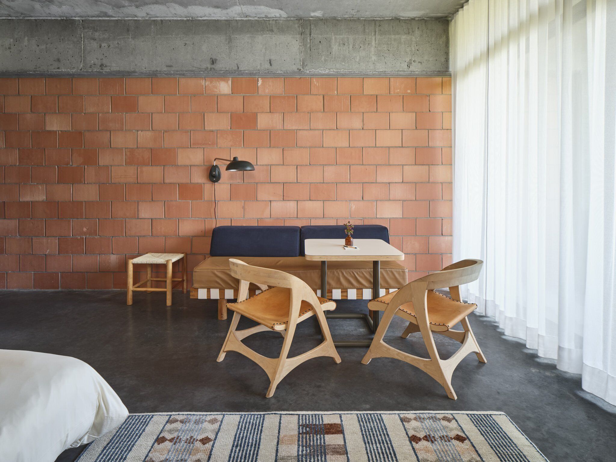 Una habitación acogedora con pared de ladrillo, un sofá, una mesita y dos sillas de madera.