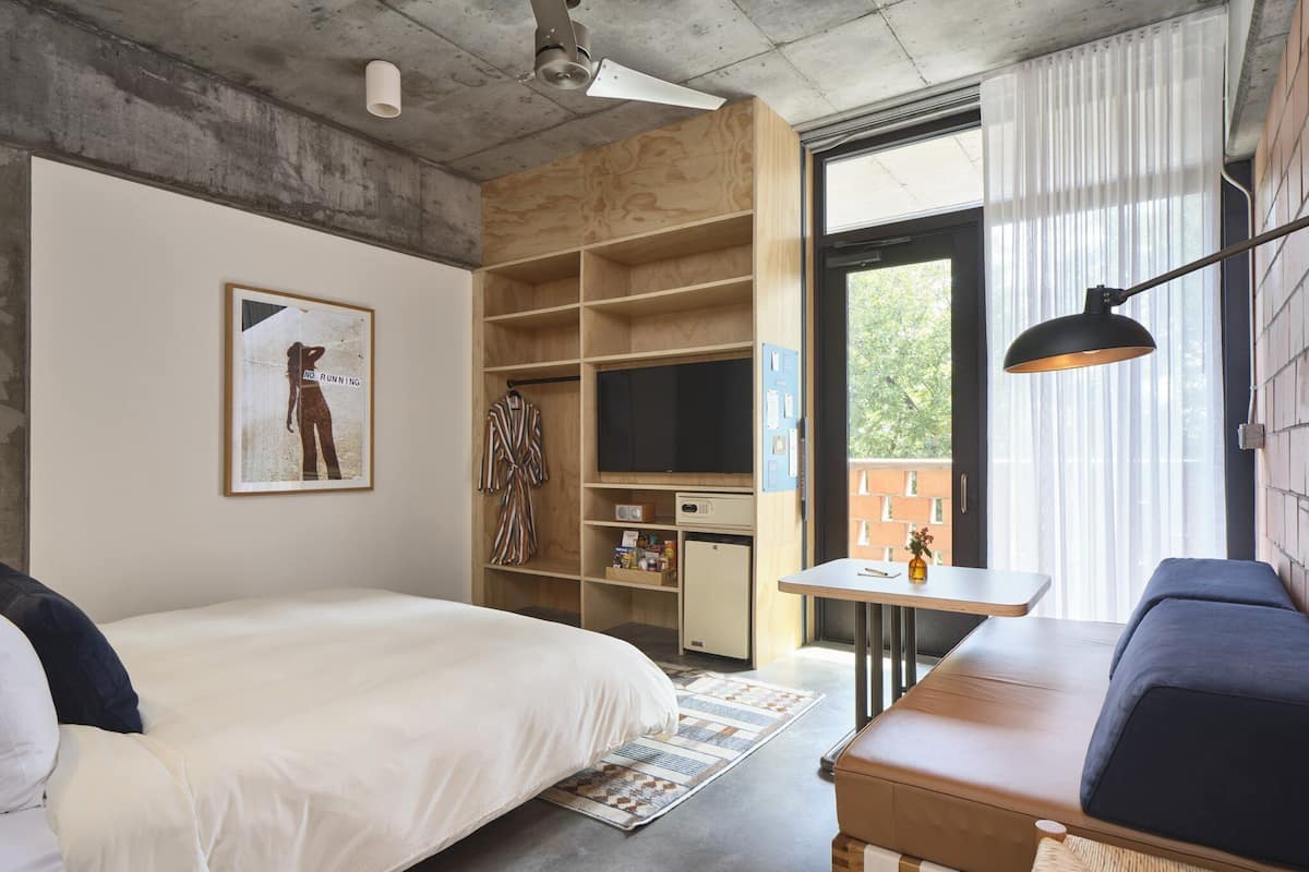Una habitación de hotel con cama, sofá, televisor, escritorio y armario.