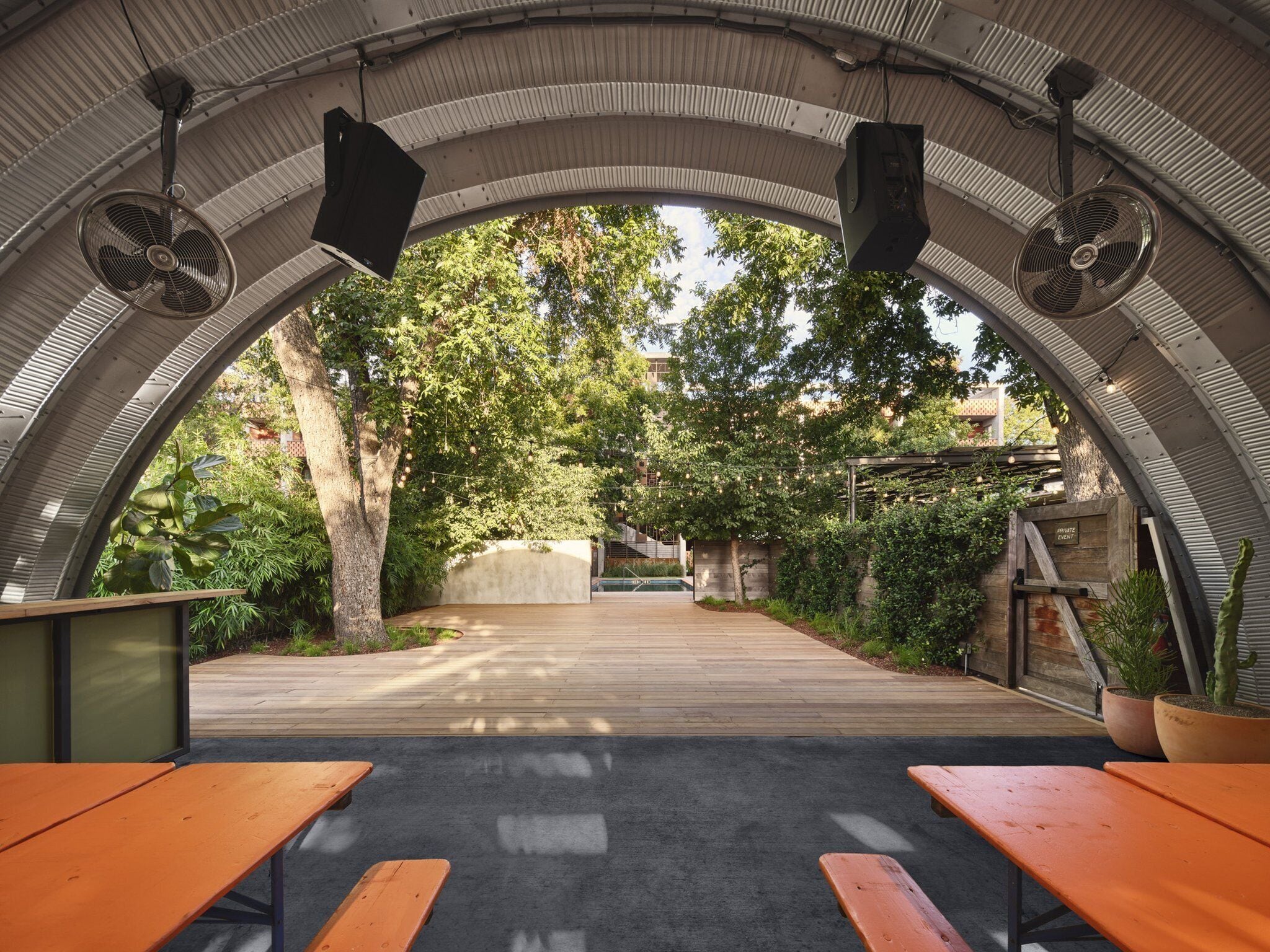 An outdoor patio area with a curved ceiling, wooden benches, and potted plants.