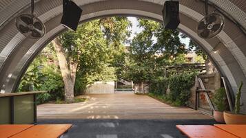 An outdoor patio area with a curved ceiling, wooden benches, and potted plants.