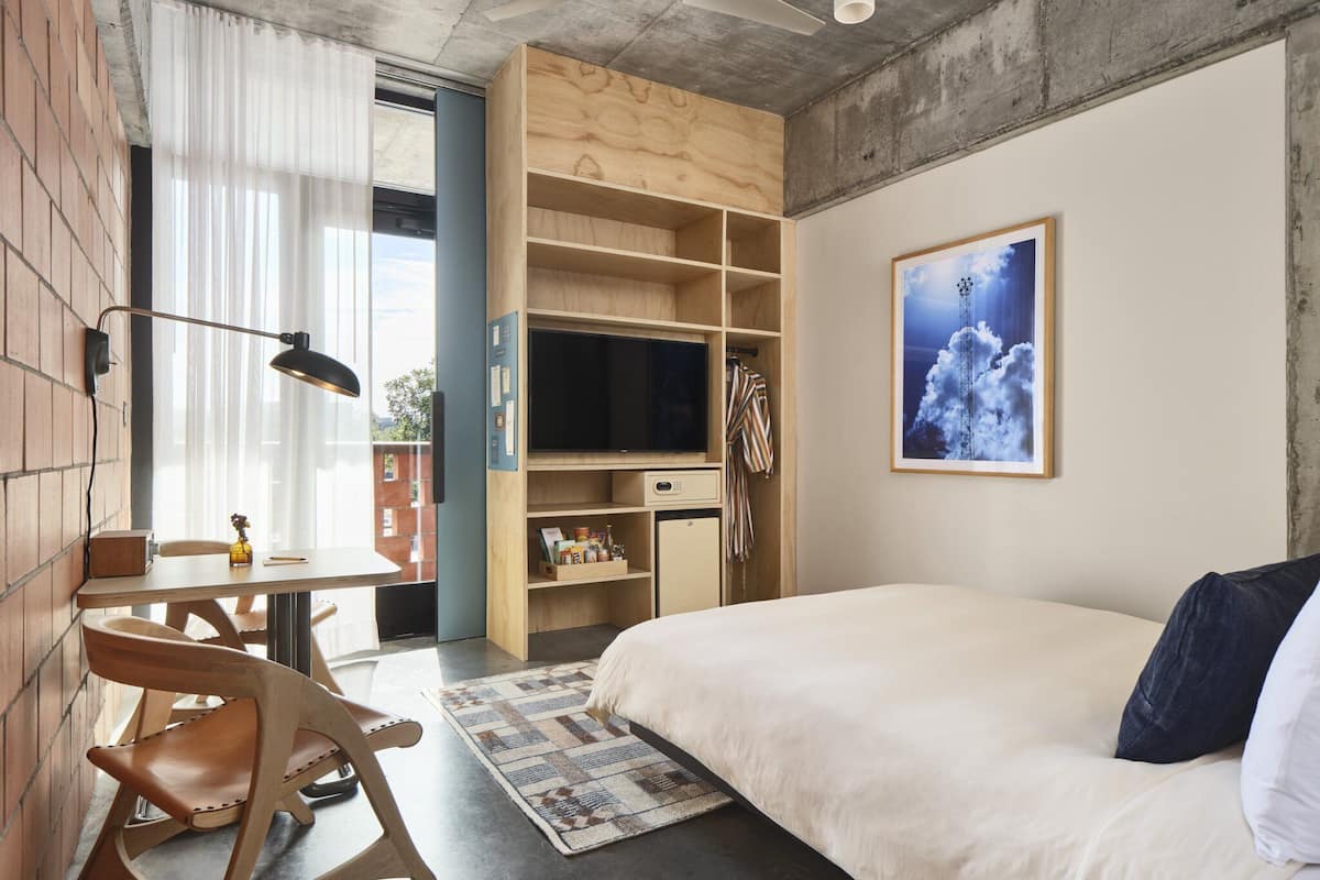 Un dormitorio con una cama, un escritorio, una silla, un televisor y una estantería.