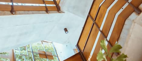 Un interior de varios niveles con una escalera que cuenta con barandas de madera y soportes metálicos.