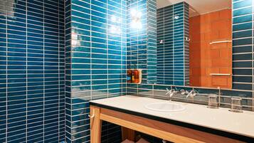 A bathroom with blue-tiled walls, a wooden vanity, a sink, and a mirror.