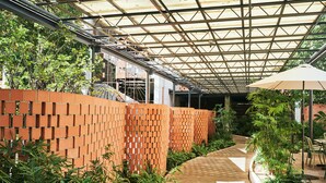 A covered walkway with brick walls, wooden flooring, and potted plants. - The Carpenter Hotel (Austin)