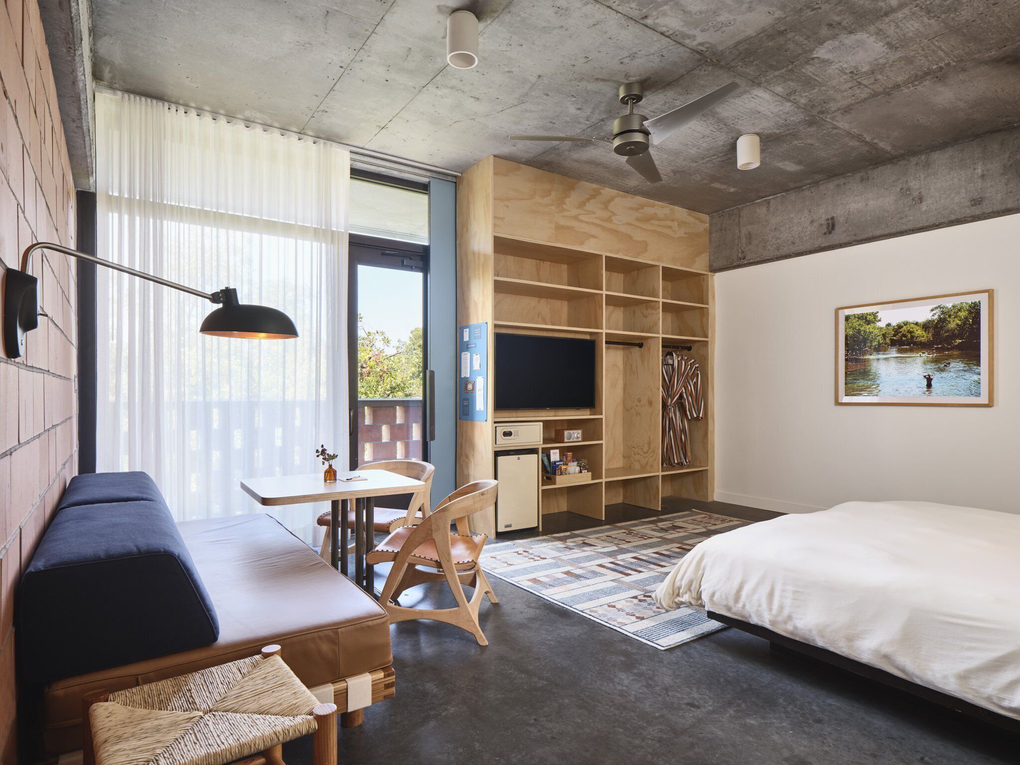 A modern bedroom with a large bed, a desk with a chair, a TV, and a wardrobe.