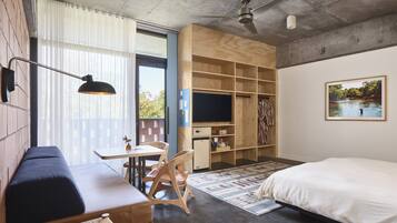 Ein modernes Schlafzimmer mit einem großen Bett, einem Schreibtisch mit Stuhl, einem Fernseher und einem Kleiderschrank.