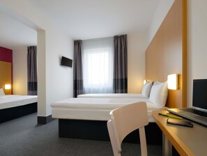 A hotel room with a bed, a desk with a laptop, a chair, and a TV on the wall. - B&B Hotel Prague-City (Prague)