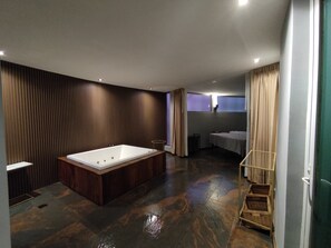 A modern bathroom with a large bathtub, a shower area, and a vanity with a mirror.