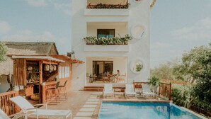 A modern building with a pool, outdoor seating, and a bar area. - Hotel Casa HX - Adults Only (Isla Holbox)