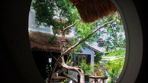 An outdoor dining area with tables and chairs, surrounded by trees and a thatched-roof structure. - Hotel Casa HX - Adults Only (Isla Holbox)