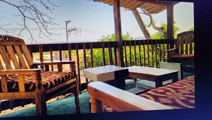 An outdoor seating area with wooden furniture and a view of greenery and a power line.