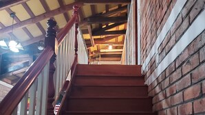 A wooden staircase with a brick wall on one side and a wooden railing.