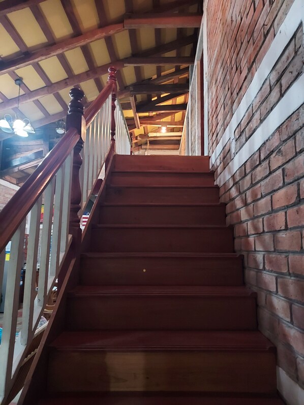 A wooden staircase with a brick wall on one side and a wooden railing.