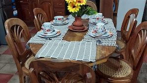 Una mesa de comedor de madera con mantel a cuadros, rodeada de sillas de madera con asientos de mimbre.