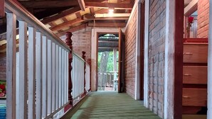 A corridor with a wooden ceiling, brick walls, and a green carpet.