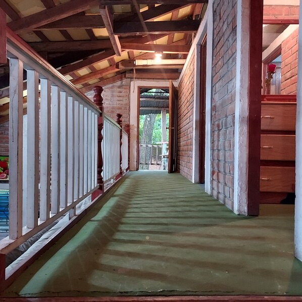 Un couloir avec un plafond en bois, des murs en briques et une moquette verte.