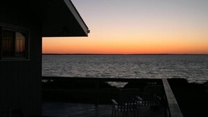A view from a balcony overlooking a body of water during sunset. - Waterfront - secluded beachfront 
Last Min Discount for week of August 29-Sept 5 (Portsmouth)